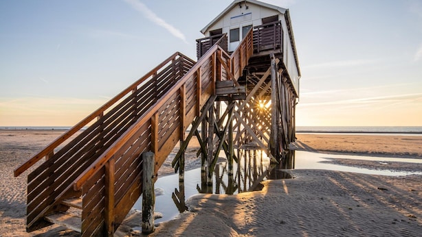 A wooden pier leading to a small building with a sloped roof and a balcony. - Ferienwohnung Direkt am Deich in St.peter-ording (St. Peter-Ording)