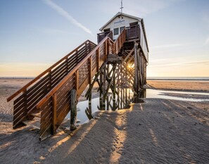 A wooden pier leading to a small building with a sloped roof and a balcony. - Ferienwohnung Direkt am Deich in St.peter-ording (St. Peter-Ording)