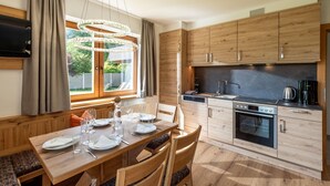 Een moderne keuken met houten kastjes, een inbouwoven en een eethoek met een tafel voor vier personen.