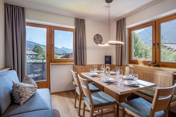 Ein Essbereich mit einem Holztisch, gedeckt für sechs Personen, umgeben von Stühlen mit gepolsterten Sitzen.