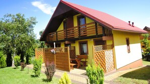 A two-story house with a red roof, wooden balcony, and a fenced garden area. - Terraced House in Rewal Near Baltic Sea Beach (Rewal)