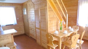 A wooden cabin with a dining table, chairs, and a bed. - Terraced House in Rewal Near Baltic Sea Beach (Rewal)