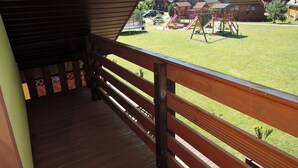 A wooden deck with a railing overlooking a playground with slides and swings. - Terraced House in Rewal Near Baltic Sea Beach (Rewal)