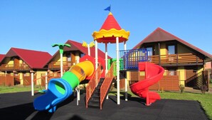 A playground with a slide, a climbing structure, and a small tower with a flag. - Terraced House in Rewal Near Baltic Sea Beach (Rewal)
