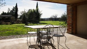 An outdoor patio with a table and chairs, a view of a grassy field, and a brick wall. - 3-star cottage in the countryside with panoramic v (Fiac)