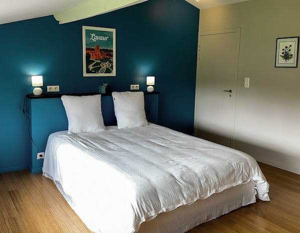 A bedroom with a bed, two bedside lamps, a framed picture on the wall, and a door. - 3-star cottage in the countryside with panoramic v (Fiac)
