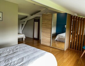 Une chambre à coucher avec un lit, un plancher en bois, un miroir et un escalier.
