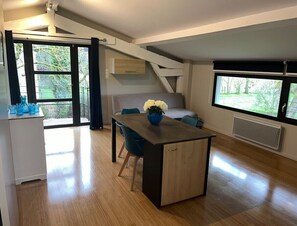 A modern living room with a wooden floor, a dining table with chairs, a sofa, and a staircase leading to an upper level. - 3-star cottage in the countryside with panoramic v (Fiac)