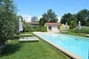 A swimming pool with white lounge chairs and umbrellas, surrounded by greenery and a small building with a tiled roof. - 3-star cottage in the countryside with panoramic v (Fiac)