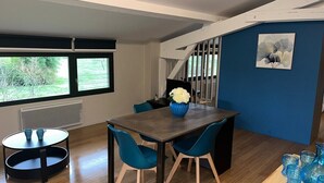 A modern dining area with a dark wooden table, blue chairs, and a vase of white flowers.