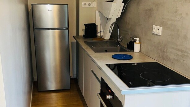 A compact kitchen with a stainless steel refrigerator, a gas stove, and a sink.
