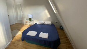 A bedroom with a bed, a nightstand, a lamp, and a window. - Studio Victoria - Centre de Paris (Paris)