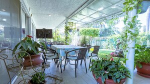 An outdoor patio with a table and chairs, surrounded by potted plants and a garden view. - New house with pool and grill area (Cuernavaca)
