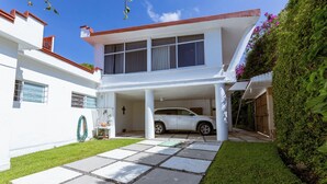 A two-story house with a car parked in the garage. - New house with pool and grill area (Cuernavaca)