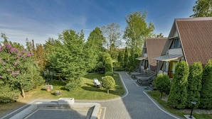 A modern building with a sloped roof, a paved driveway, and a well-maintained garden with trees and shrubs. - Holiday Homes With air Conditioning, Large Garden (Kołobrzeg)