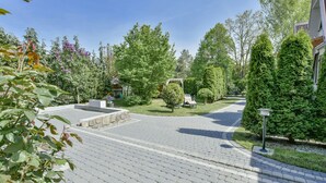 A paved pathway leading to a house with a garden, a bench, and a lamp post. - Holiday Homes With air Conditioning, Large Garden (Kołobrzeg)