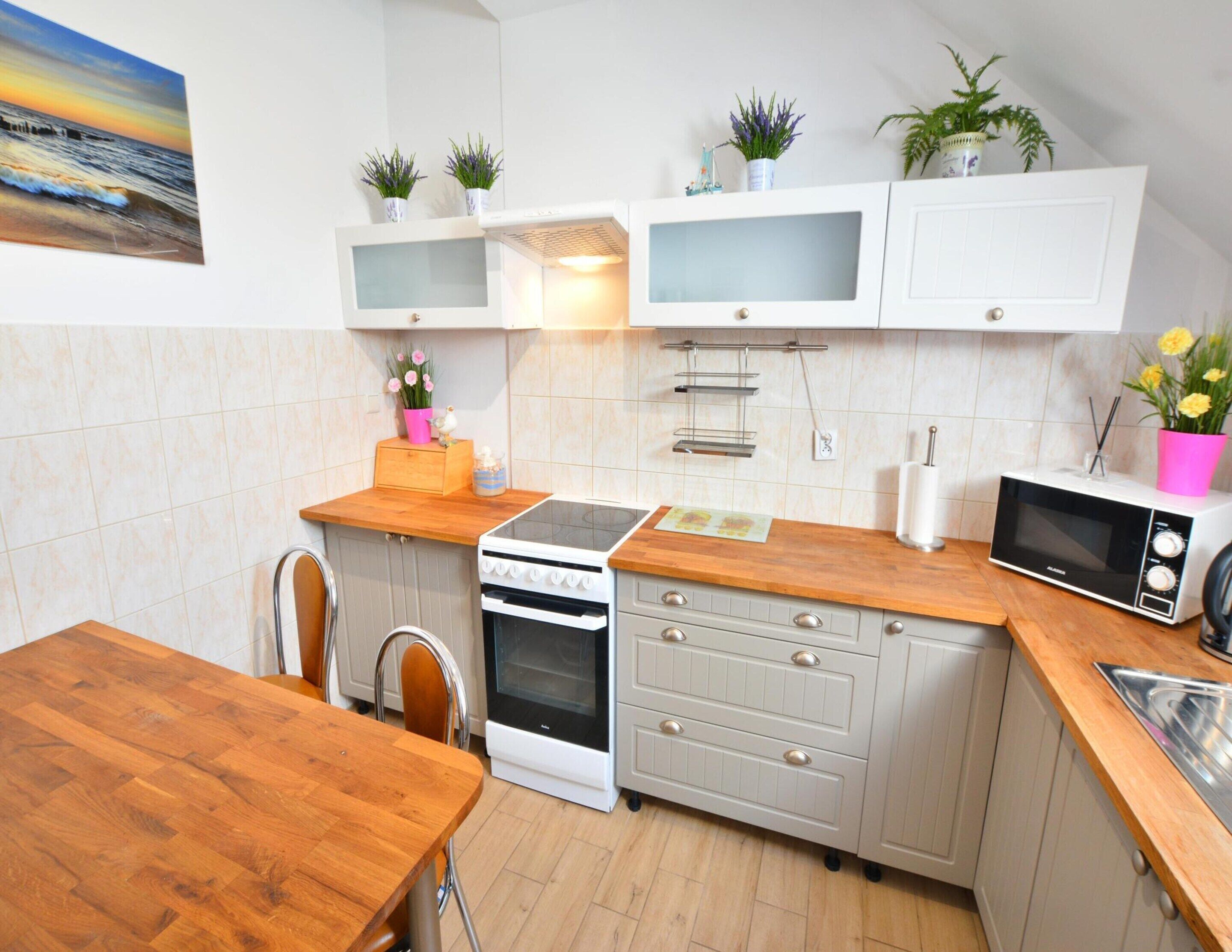 A modern kitchen with white cabinets, a wooden countertop, a stove, an oven, a microwave, and a dining table.