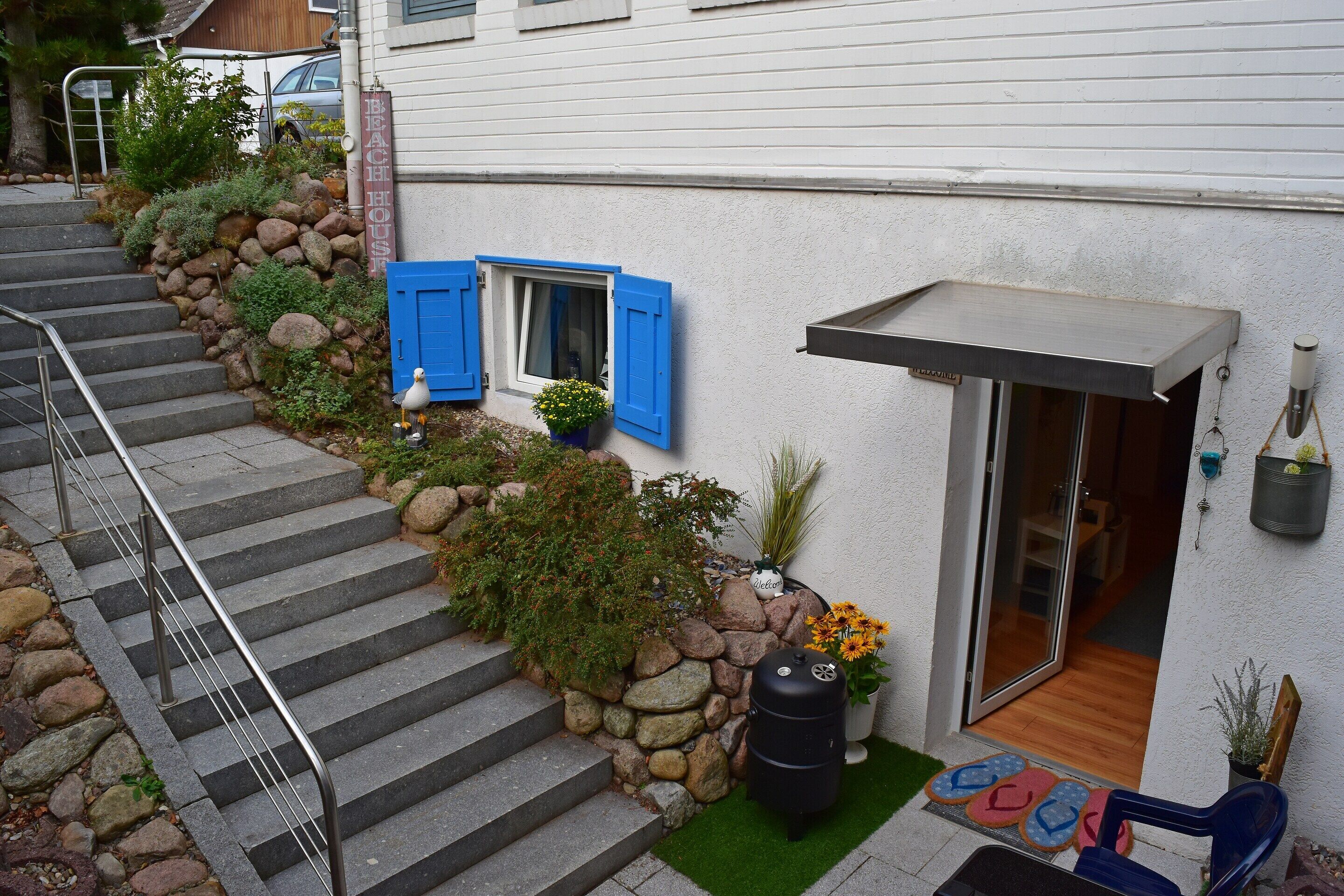 A modern house with a stone staircase, a small garden, and a wooden door.