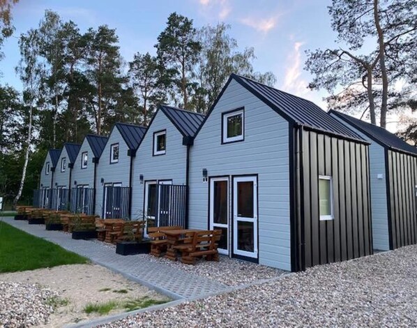 A row of cabins with a gravel path leading to wooden benches.