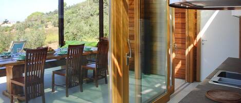 Un área de comedor con una mesa, sillas, un ventanal corredero y vistas al exterior.