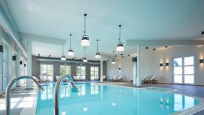 An indoor swimming pool with clear water, surrounded by lounge chairs and a tiled floor. - Moderne Wohnung im Rugana Feriendorf (Dranske)