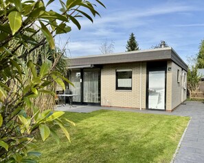 Uma casa moderna com telhado plano, fachada de tijolos e um pequeno pátio com mesa e cadeiras.