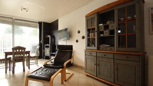 Ein Wohnzimmer mit einem schwarzen Ledersessel, einem Holzesstisch und einer Vitrine.