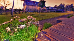 Une terrasse en bois avec une balançoire et une maison en arrière-plan.
