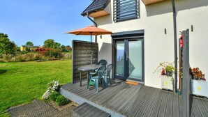 Une maison moderne dotée d’une terrasse, d’une antenne parabolique et d’une porte de garage.