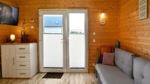 Une pièce chaleureuse aménagée comme une cabane, avec un canapé, une armoire et un téléviseur fixé au mur.