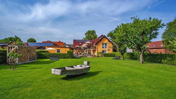 A residential area with houses, a boat, and a well-maintained lawn. - Apartment on the Spree River in Schlepzig (Schlepzig)