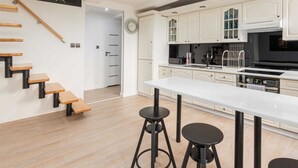 Una cocina moderna con armarios blancos, encimera negra y una escalera de madera.