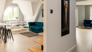 Una sala de estar moderna con comedor, un sofá color turquesa y una obra de arte grande con la trompa de un elefante en la pared.