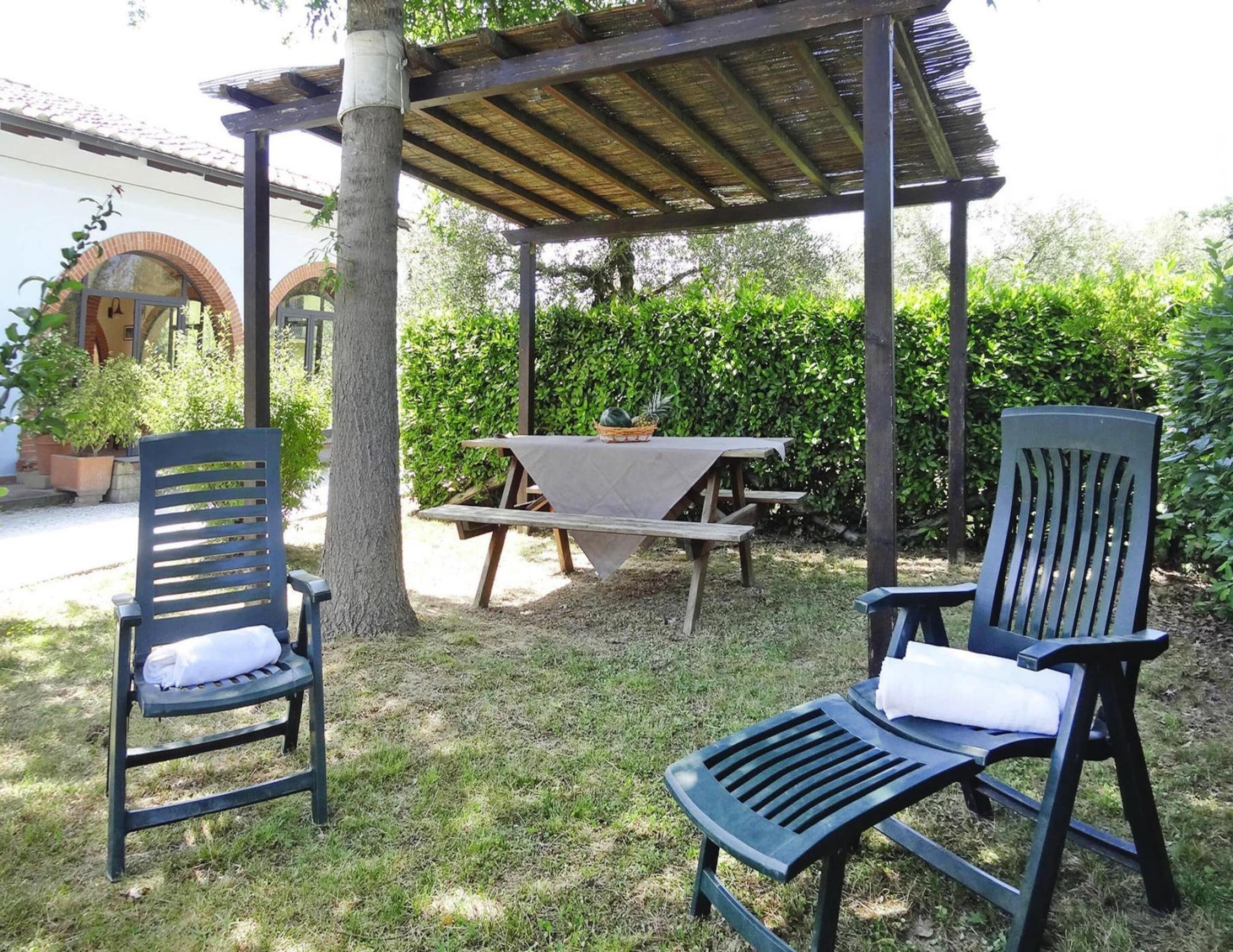 Un espace extérieur aménagé avec deux chaises et une table de pique-nique, le tout installé sous une pergola.