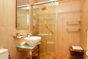 A modern bathroom with a glass-enclosed shower, a white sink, and a wooden stool. - Holiday Home Meloneras Hills, Meloneras (San Bartolomé de Tirajana)