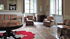 A spacious living room with a large round table, several armchairs, and a patterned rug. - Residence Villa Pitiana at Donnini (Reggello)