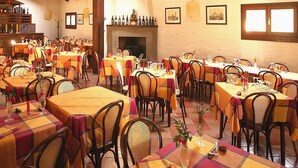 A dining area with multiple tables set for meals, wooden beams on the ceiling, and a fireplace. - Rustic Escape in Palazzuolo Stay (Palazzuolo sul Senio)