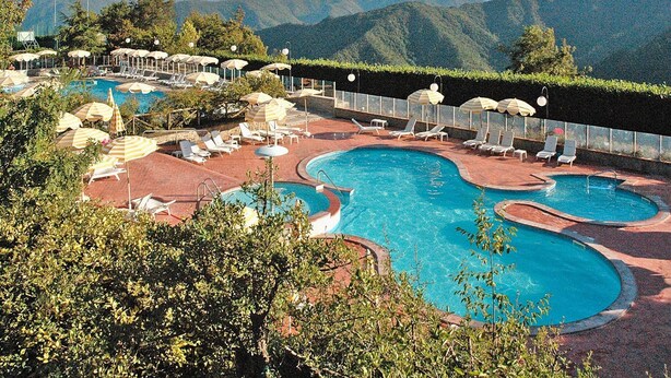 A pool area with multiple sun loungers and umbrellas, surrounded by lush greenery and mountains in the background. - Rustic Escape in Palazzuolo Stay (Palazzuolo sul Senio)