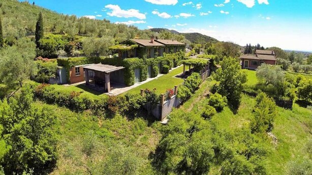 Una extensa propiedad con varias construcciones rodeadas de abundante vegetación y colinas.
