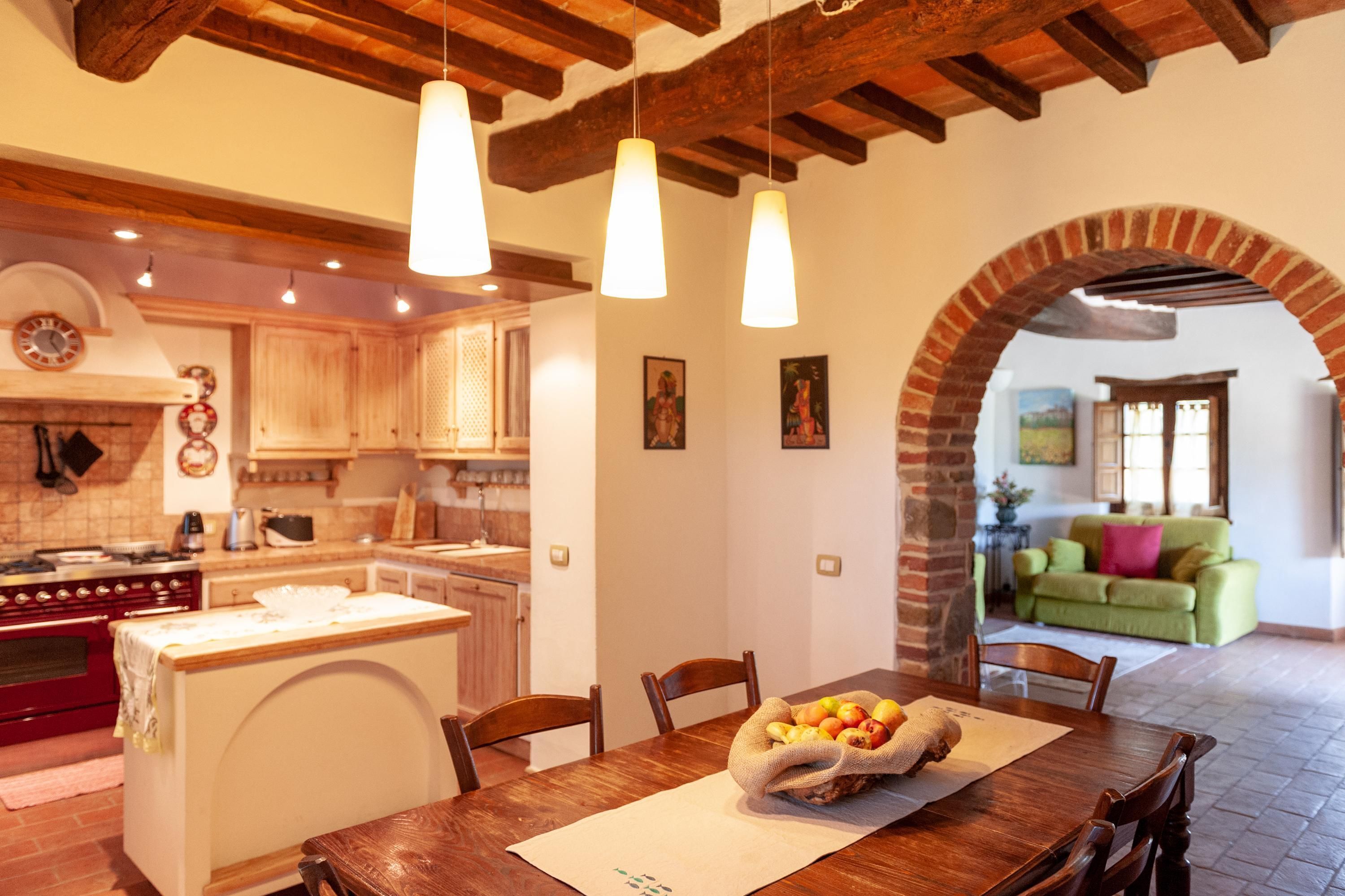 A cozy dining area with a wooden table, chairs, and a fruit basket.