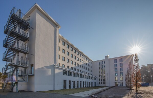 A modern building with multiple floors, a central courtyard, and a parking area. - Dunenresidenz Prora (Binz)