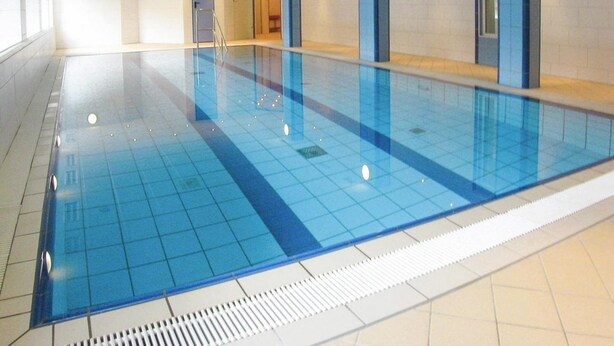 A large indoor swimming pool with clear blue tiles and a tiled floor. - Apartment in Cuxhaven mit Gemeinschaftspool (Cuxhaven)