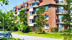 A multi-story residential building with brick exterior, balconies, and a paved driveway. - Apartment in Cuxhaven mit Gemeinschaftspool (Cuxhaven)