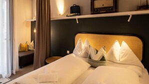 Ein Hotelzimmer mit Bett, Kissen, Nachttisch, Radio und einem Fenster mit Vorhängen.
