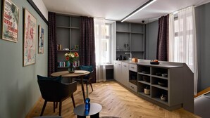 Eine moderne Küche mit grauen Schränken, eine Essecke mit einem runden Tisch und Stühlen sowie ein Bücherregal voller Bücher.