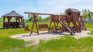 A playground with a swing set, slide, and climbing structure. - Apartment in Darlowko Near Beach & Water Park (Darlowo)