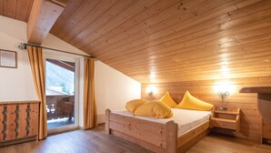 A wooden cabin bedroom with a bed, a nightstand, and a window with curtains. - Apartment in Milders Near Stubai Glacier (Neustift Im Stubaital)