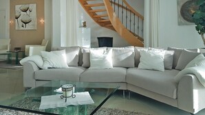Un salon moderne avec un canapé beige, une table basse en verre et un escalier en bois.