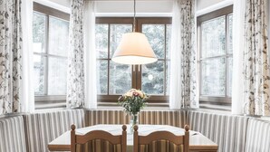 Un coin repas avec une table et deux chaises, une lampe suspendue et un vase rempli de fleurs.