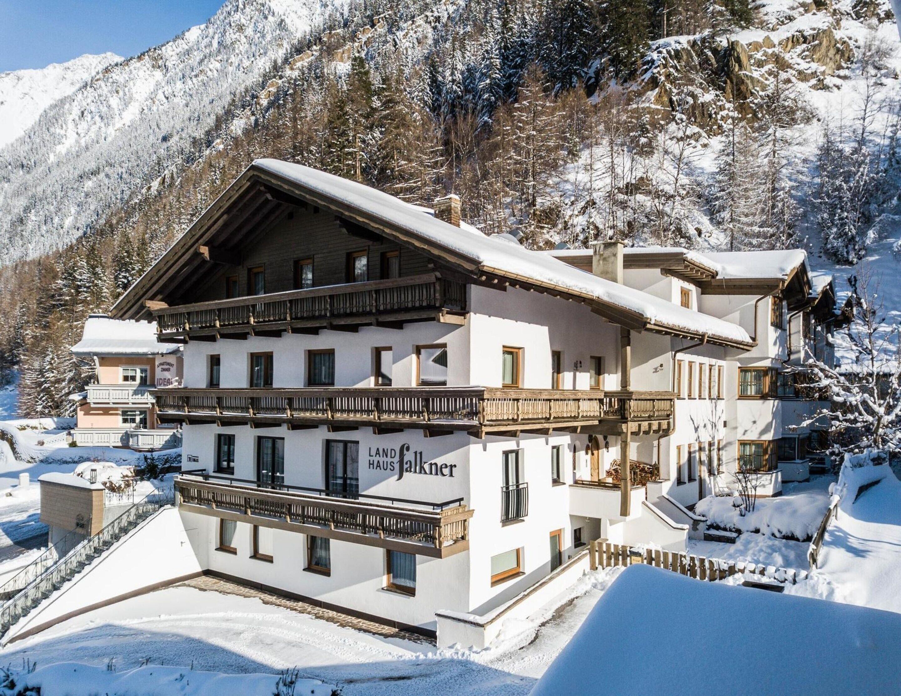 A multi-story hotel with a traditional Alpine architectural style, featuring balconies and a prominent sign for 'Landhaus Falkner'.